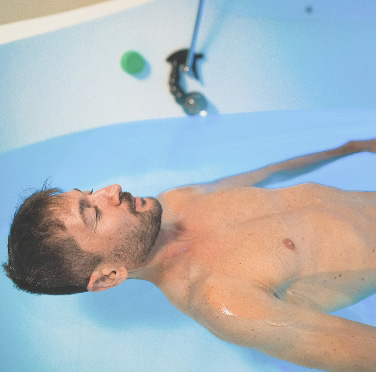 man relaxing himself while floating in floatation tank therapy