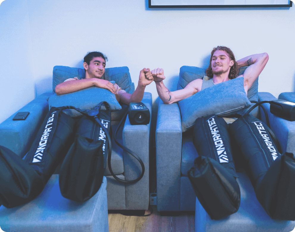 two men fist bumping while they use their normatec boots