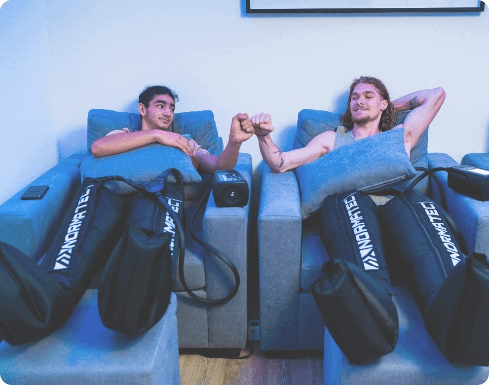 two men fist bumping while doing normatec boots sydney