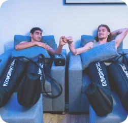 man fistbumping man while doing normatec boots